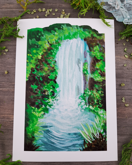 An image of a 5"x7" mini print surrounded by crystals and moss. The sticker features a vertical landscape with foliage and a waterfall, which was painted with acrylic inks.